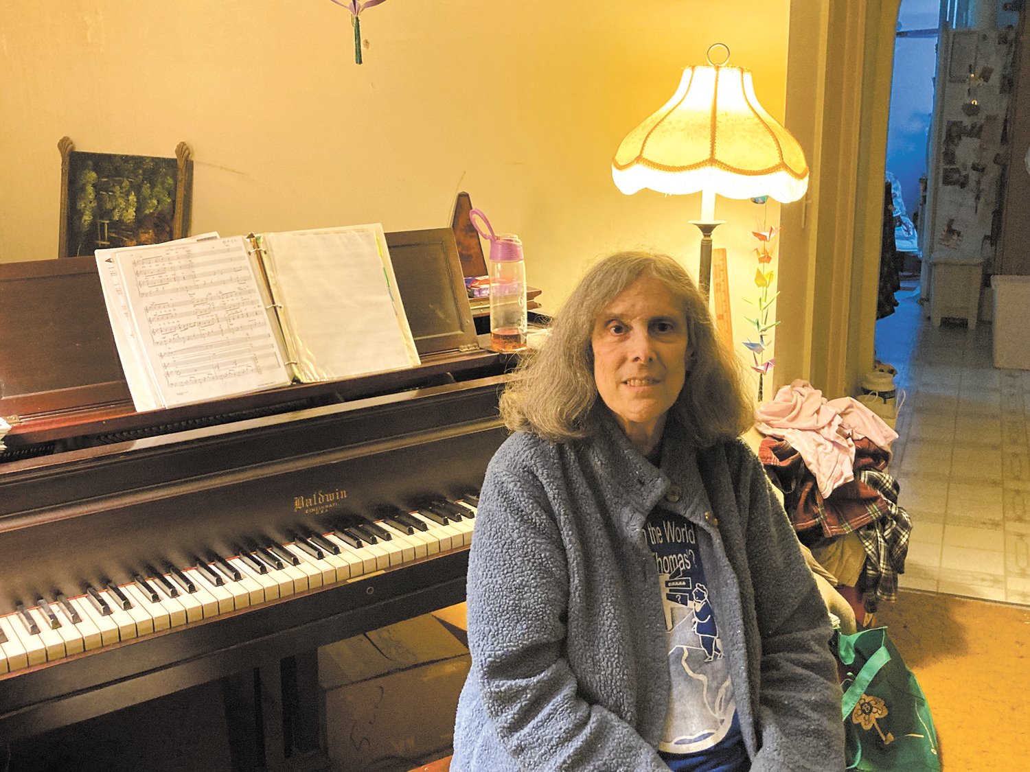 BACK HOME IN CHEPACHET: Kathleen Wikstrom sits at her piano at her Chepachet home. She started teaching piano at age 14 and went on to earn a degree in electrical-mechanical engineering from the New England Institute of Technology. She also spent time as a first responder, playing piano for churches and teaching piano and voice. (Herald photo)